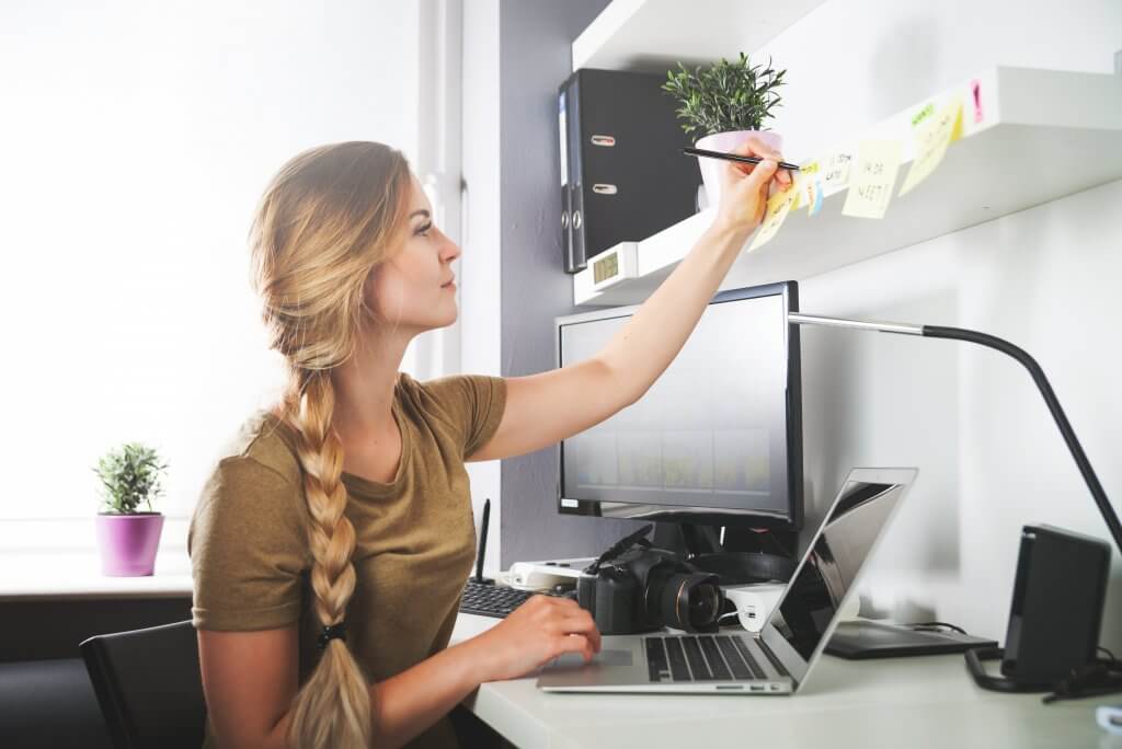 woman writing on a post it note