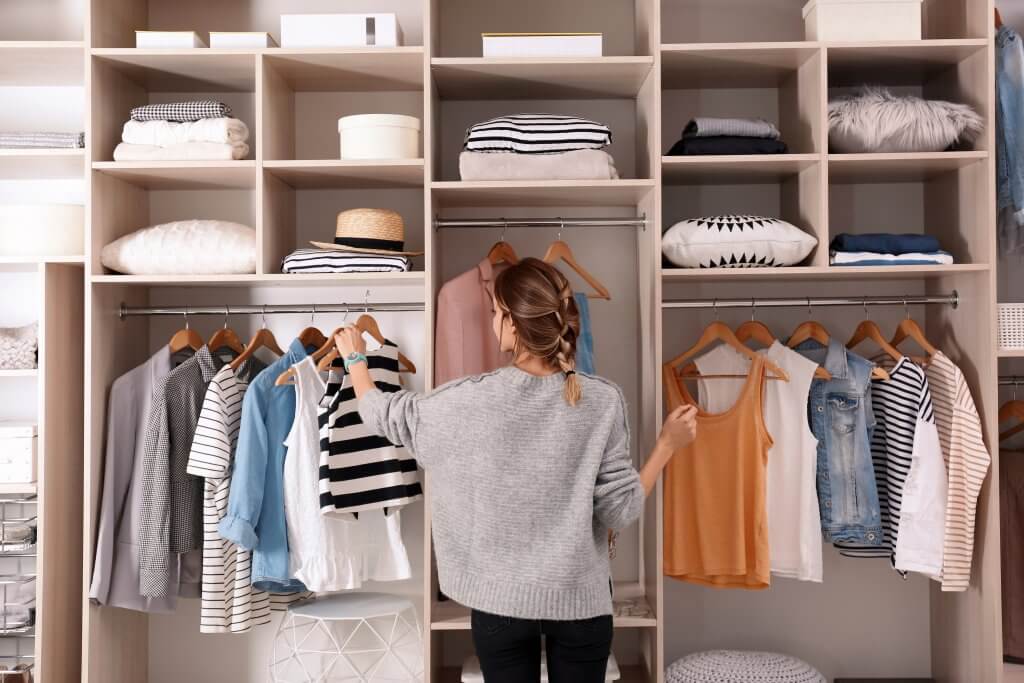 woman looking at clothes in closet