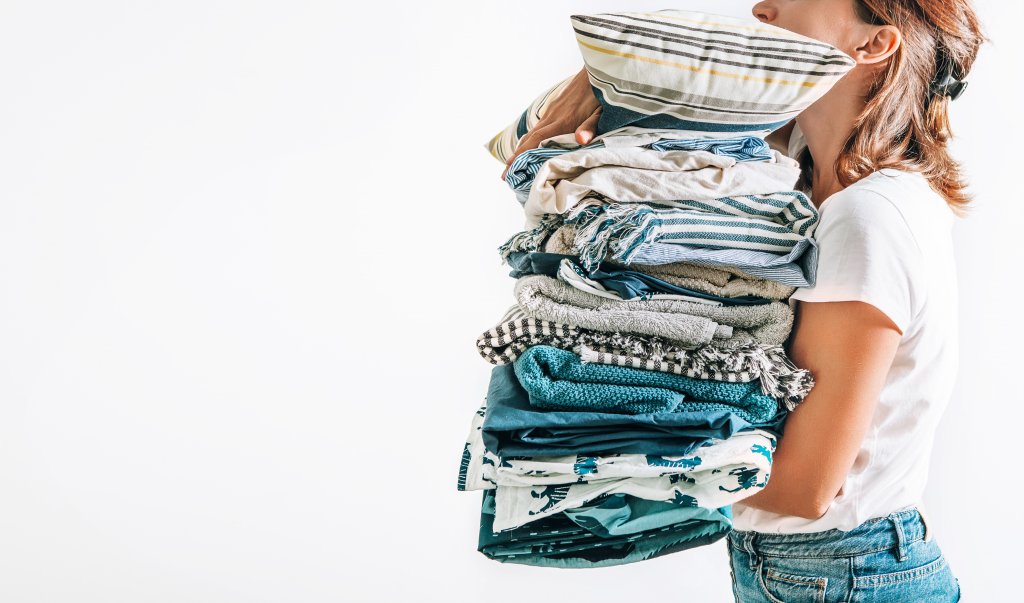 woman holding stack of linens and pillows