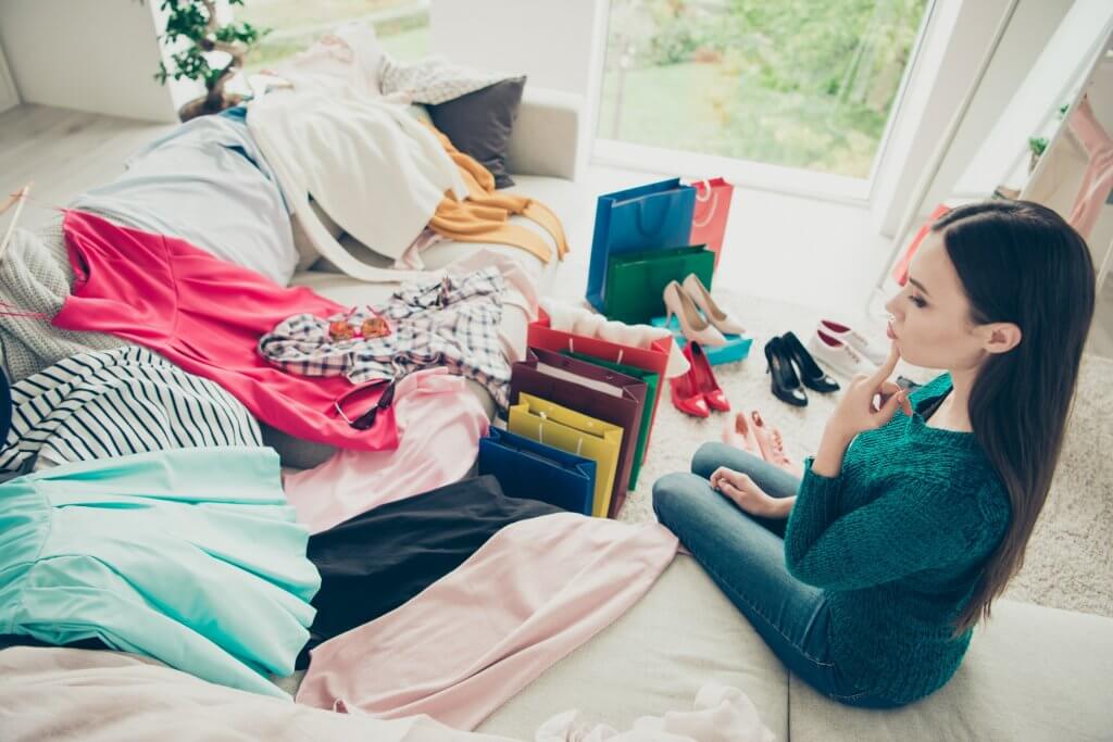 woman looking at pile of recently purchased clothes