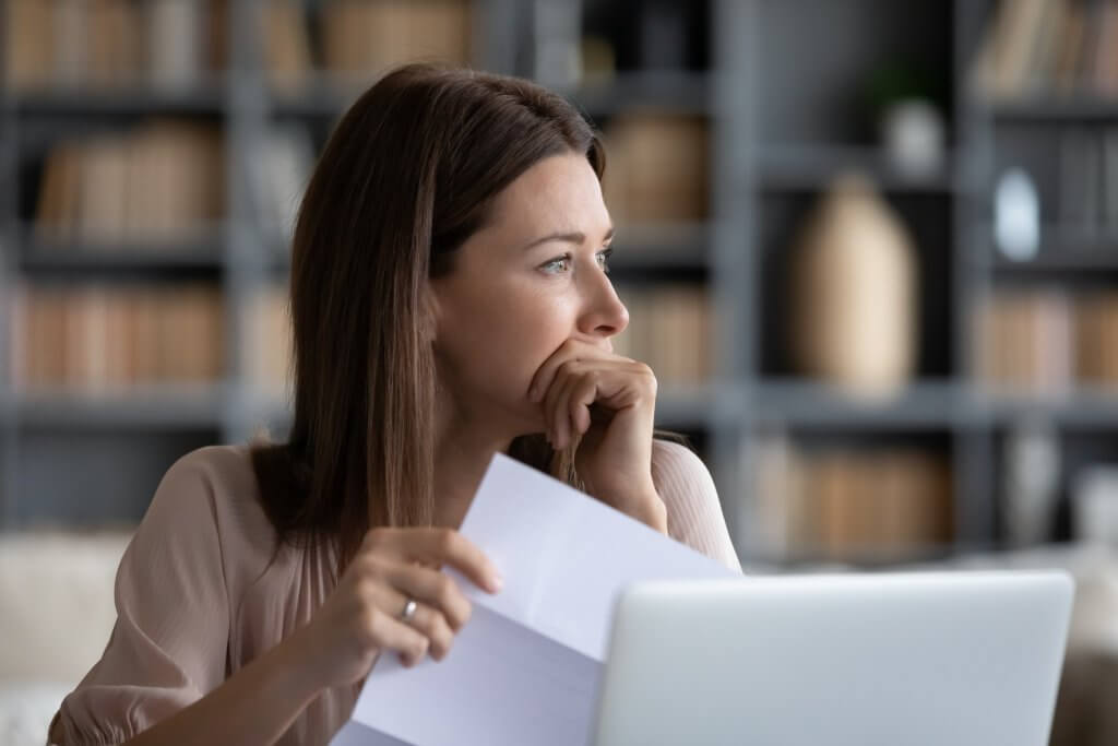woman holding paper and looking stressed