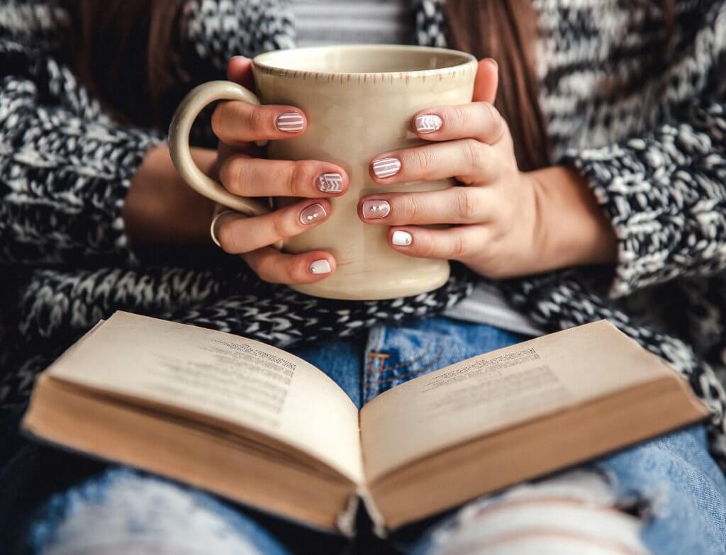 woman holding a mug and reading a book