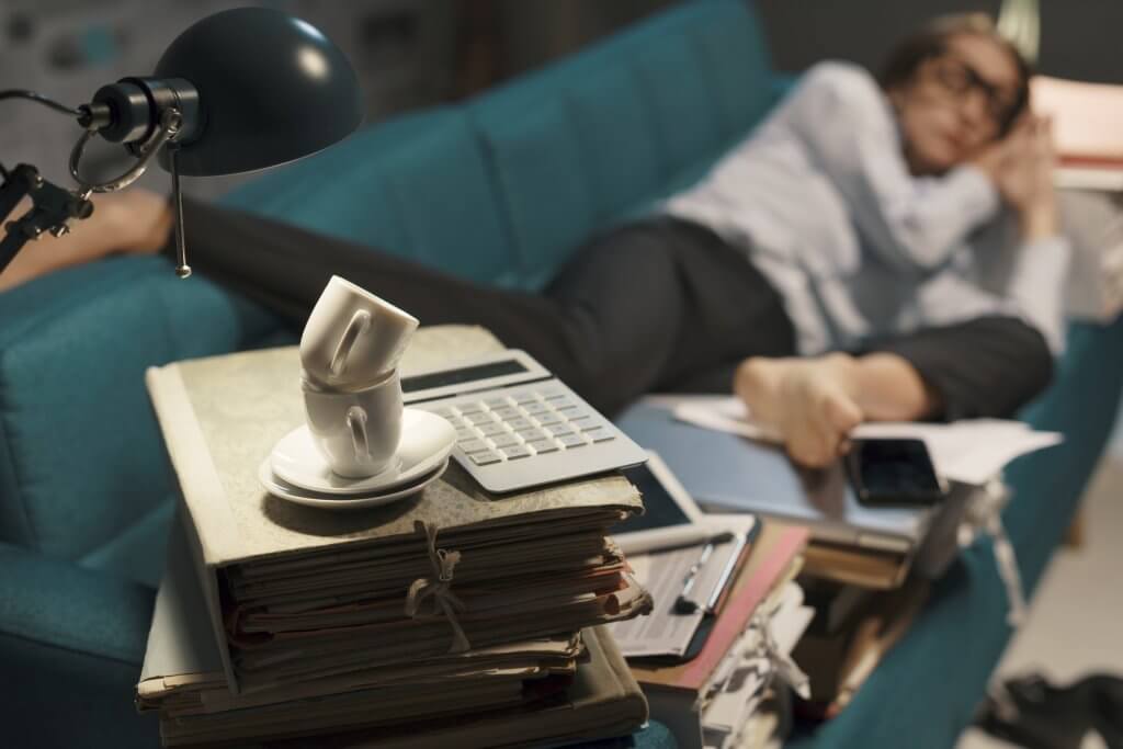 tired woman sleeping on couch in cluttered room