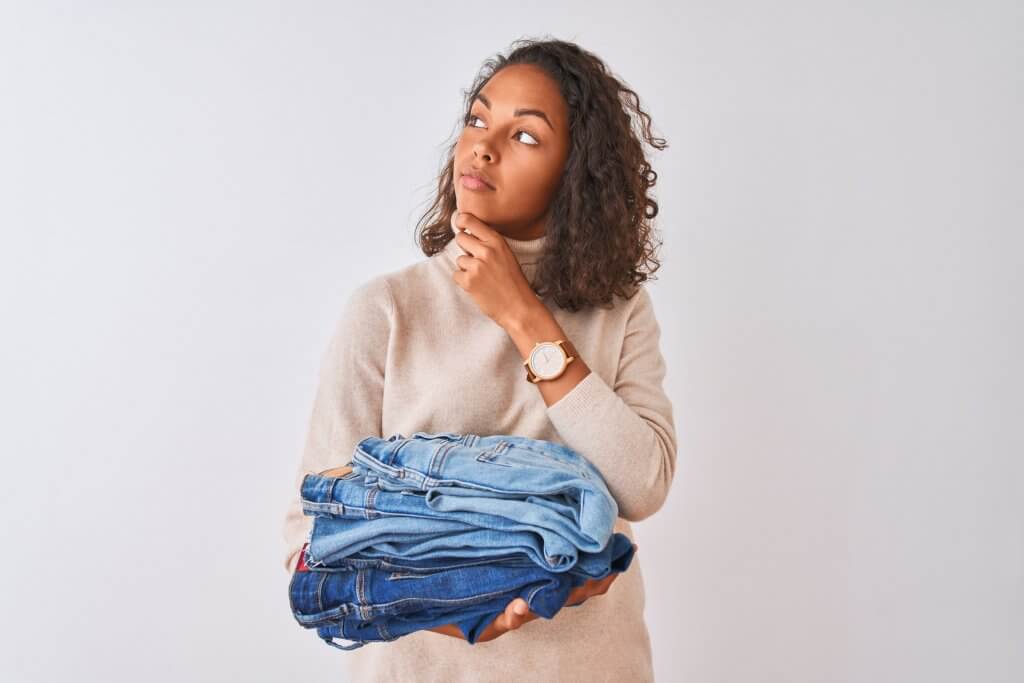 woman thinking while holding jeans