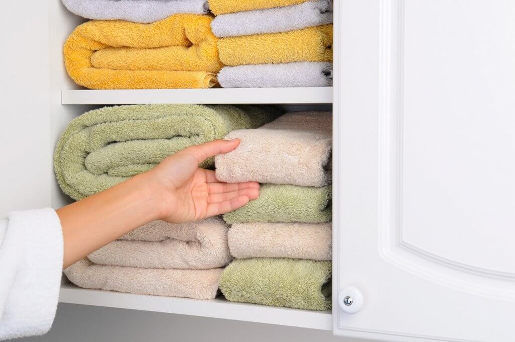 woman grabbing a towel off a shelf