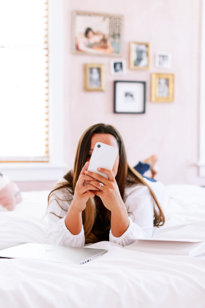 woman laying on bed looking at cellphone