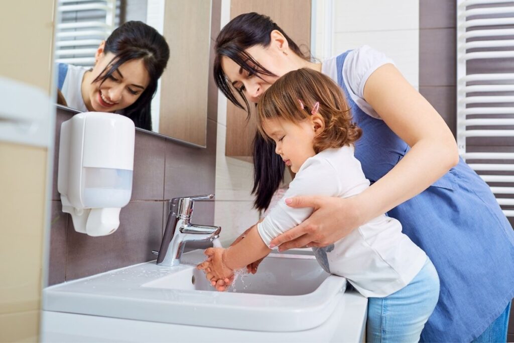 mom helping daughter wash hands