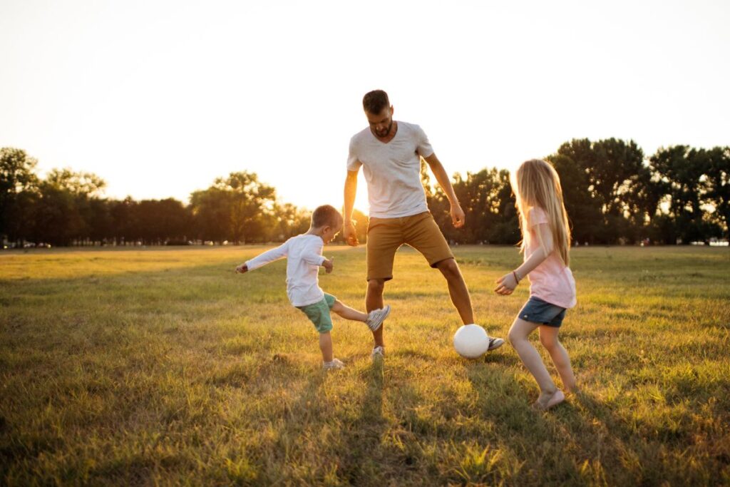 kids kicking ball with dad