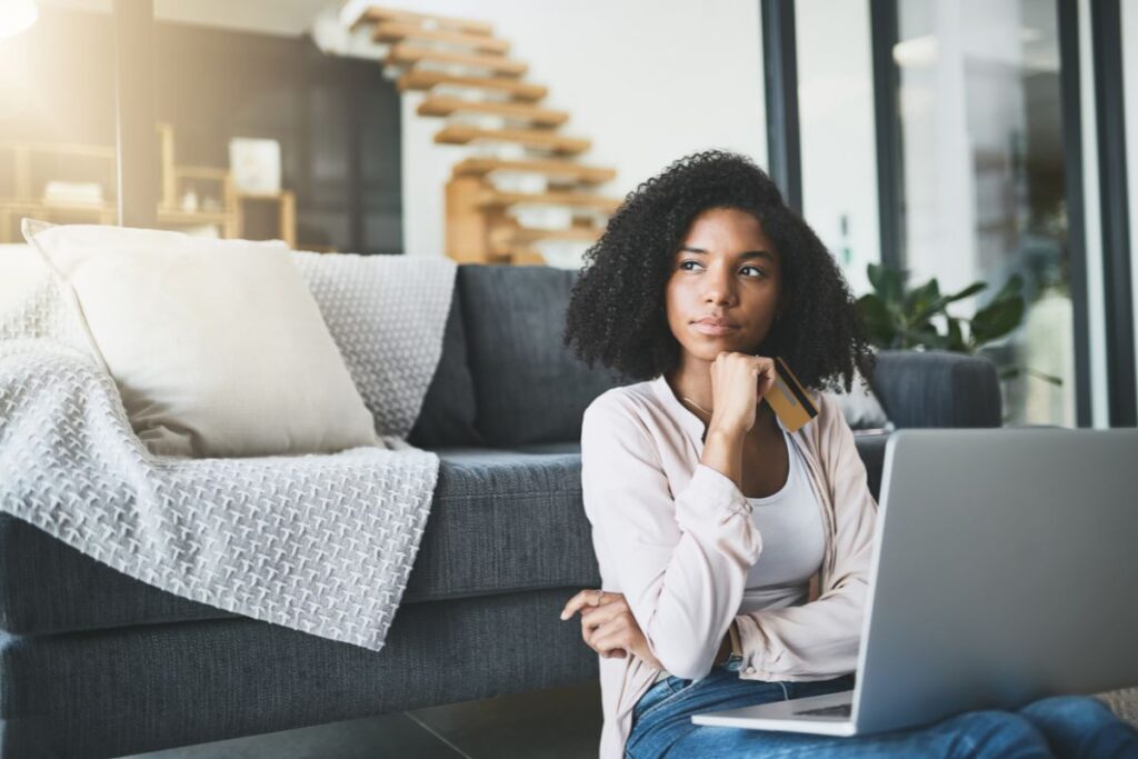 woman holding credit card while using computer