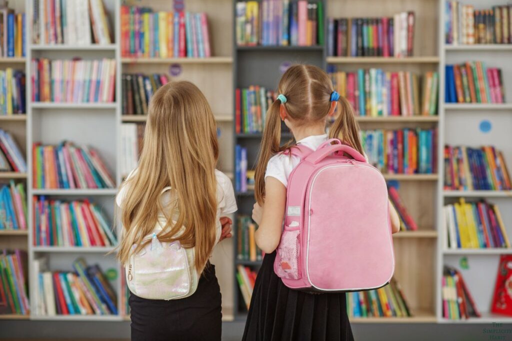 girls looking at books in school library