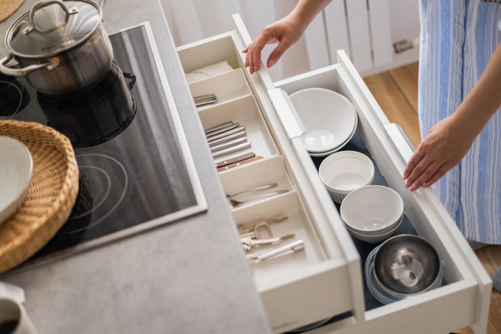 woman putting items away in kitchen drawers