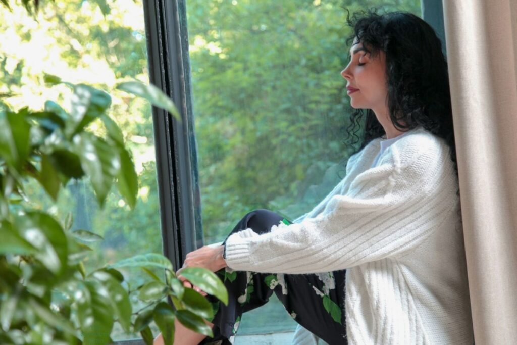 peaceful woman sitting in a windowsill